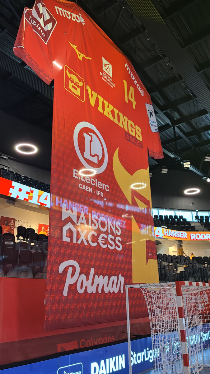 Maillot géant domicile rouge floqué #14 suspendu dans l'arène — Vikings Caen, handball Daikin StarLigue