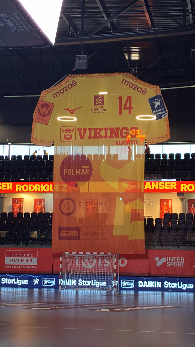 Maillot géant extérieur jaune floqué #14 suspendu dans l'arène — Vikings Caen, handball Daikin StarLigue